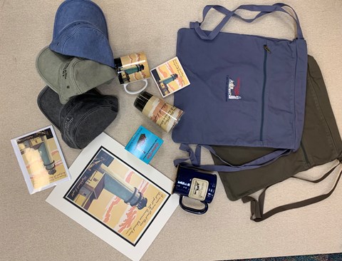 Backpacks, photos, painting, hats, magnets, and a cup laid out to display items for sale.