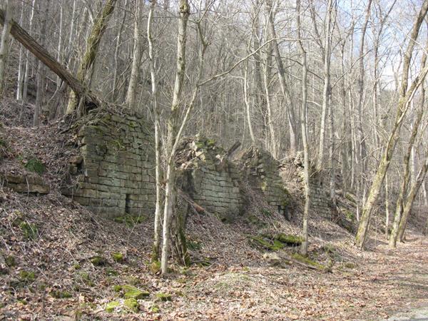 Brick beehive shaped mounds sit to the left of the trail among barren trees.
