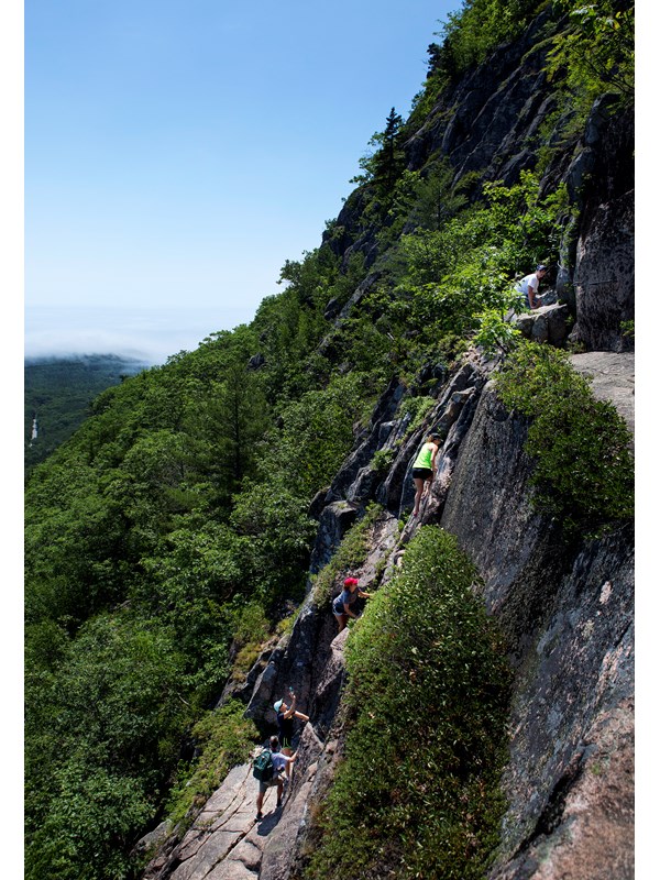 Hikers ascend a cliff with iron rungs