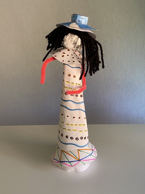 Paper doll with orange arms and blue hat.