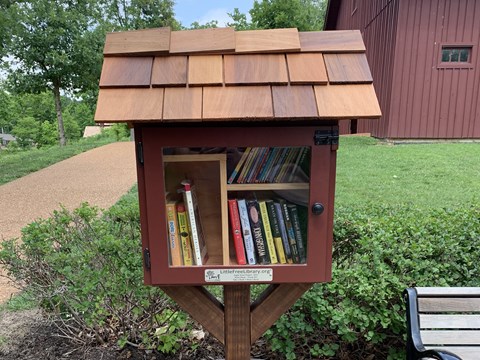 Collection of books inside red wooden box with cedar shingle roof.
