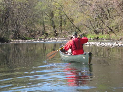 Man in a green canoe paddles down the Blackstone River