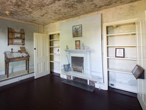 The parlor in the Poe House, a small room with illustrations of furniture but no real furniture.