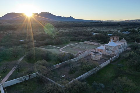 aerial photo of mission grounds with sunrise over mountains in the distance
