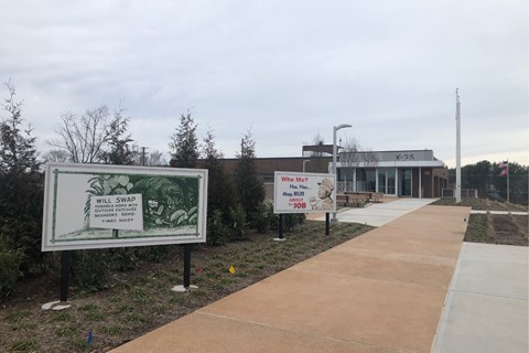 A small museum building with several retro billboards on the walkway in front of it.