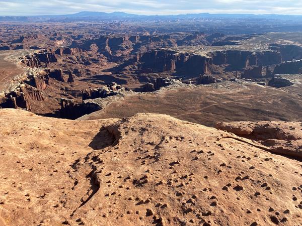A view of deep canyons from a sandstone cliff edge on a sunny day