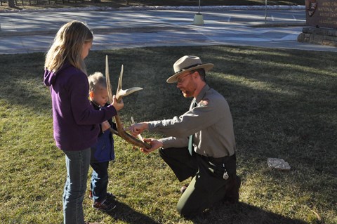 a ranger showing two children an antler