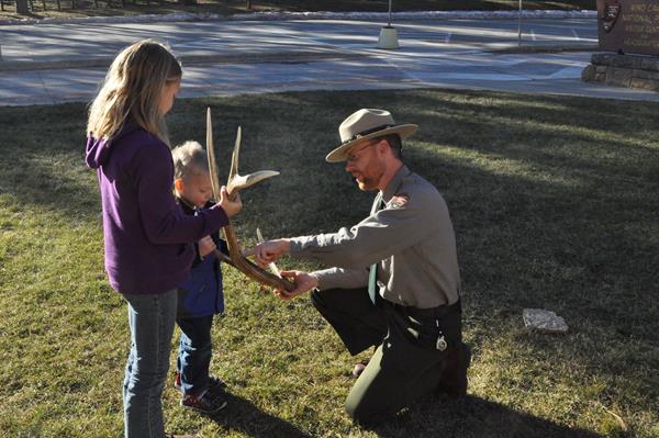 a ranger showing two children an antler