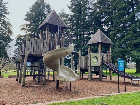 A large play structure in a bark chip playground.
