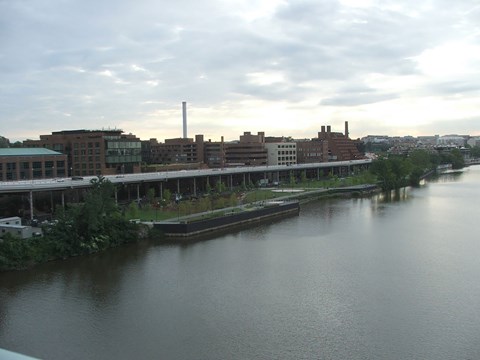 River, park and city skyline below a cloudy sky