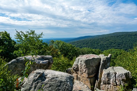 A large rocky outcrop overlooking a summertime forest.