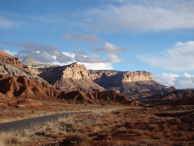 A road runs alongside red sandstone cliffs on the Scenic Drive