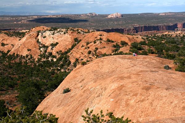 Two hikers atop sloping sandstone features