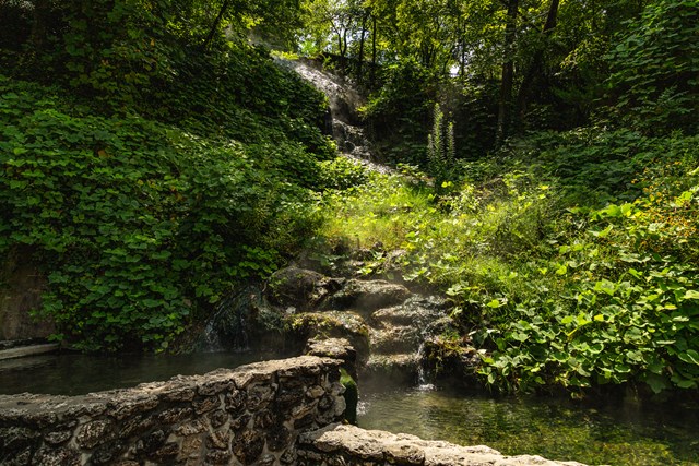 Hot spring water cascading down rock into a display pool.