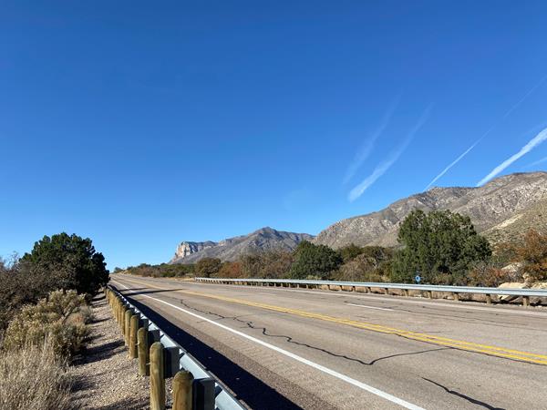 Desert mountians rise past a paved highway.