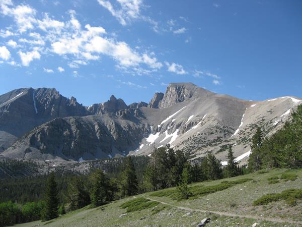 View from the summit trail of wheeler peak with a green meadow and grey mountains