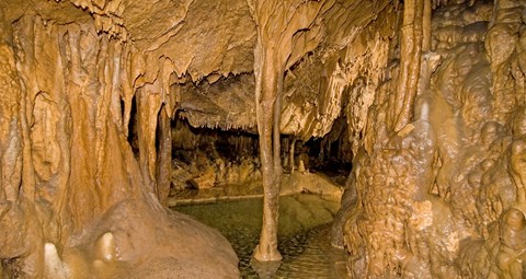 inside of cave with pool below and cave formations around it.