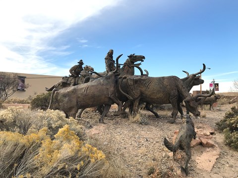 A bronze statue of oxen and traders set in the desert.