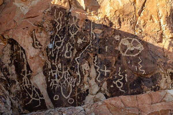 Ancient abstract images pecked into a dark rock face.