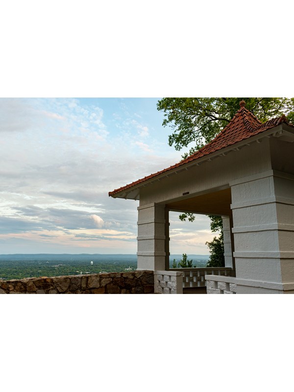 A white pagoda with a red roof sits on the edge of a hillside.