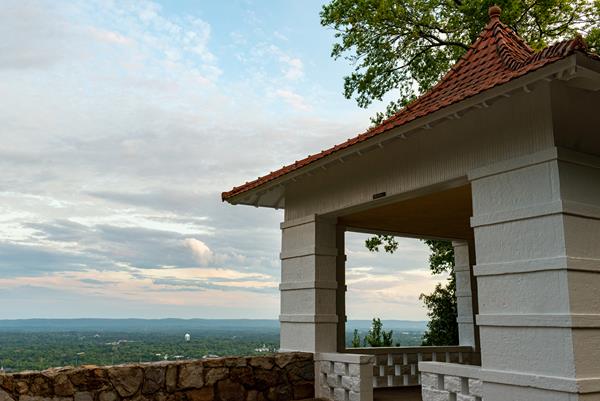 A white pagoda with a red roof sits on the edge of a hillside.