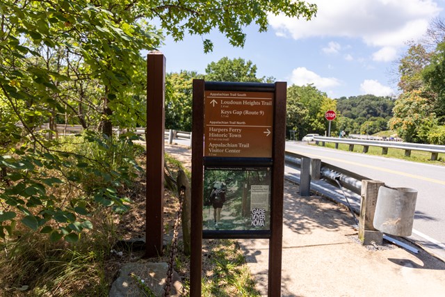 Brown trail marker at a roadside showing distances for the Appalachian Trail south to the Loudoun Heights Trail and north to Harpers Ferry Historic Town