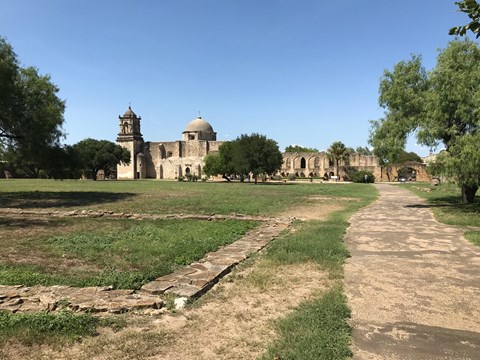 A path leads to a spanish-colonial style mission.