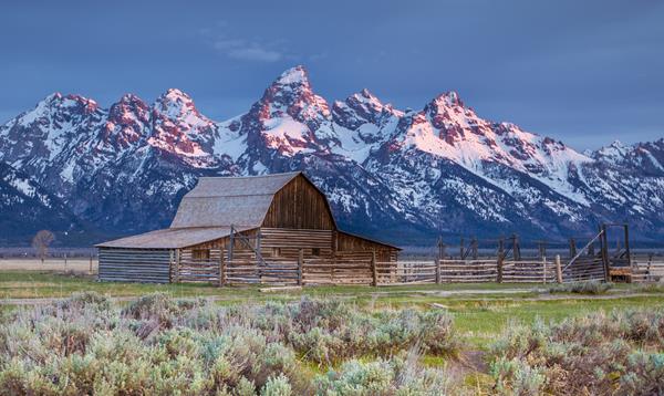 A barn with mountains behind.