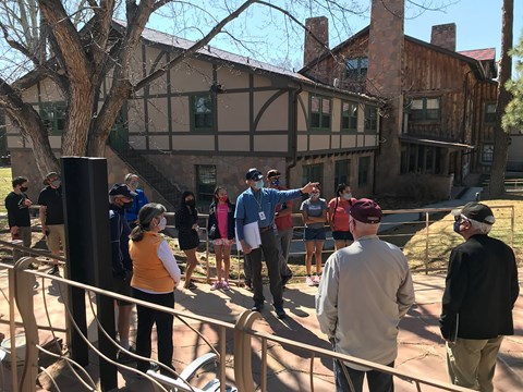 A person in a blue shirt points out a building to a group of people.