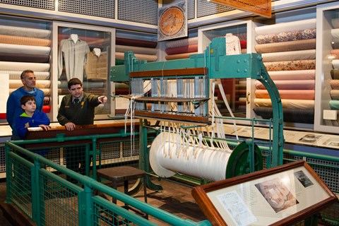 A park ranger shows off historic artifacts to a father and son in a museum