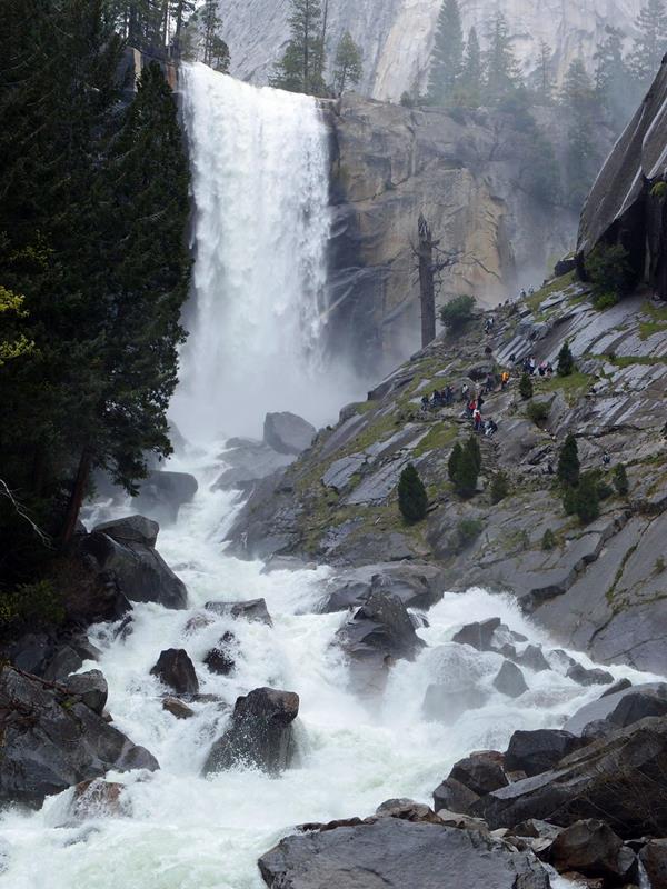 A full Vernal Fall with hikers along the rock steps of the Mist Trail