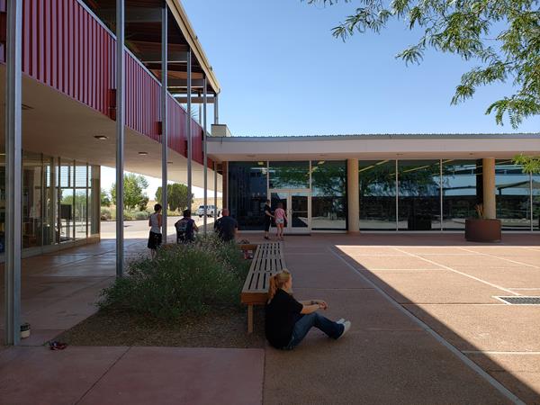 Mid-Century style architecture around people in a shady plaza.