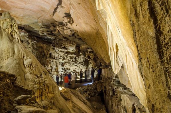 A large room made of marble walls with a group of 9 people in the distance