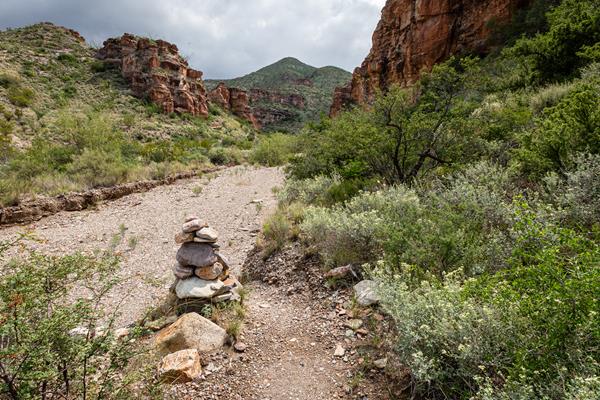 A rock cairn marks route into a sandy wash.