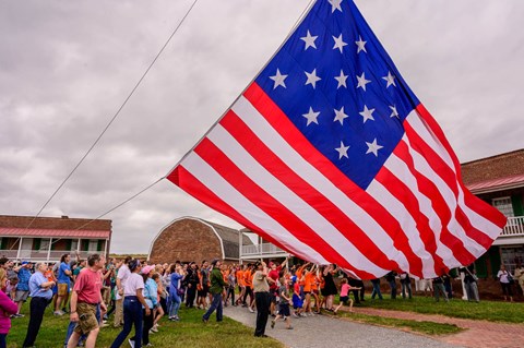 A group of visitors help raise a large garrison flag over Fort McHenry