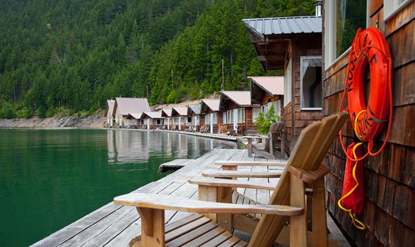 A row of cabins along a green lakeshore.