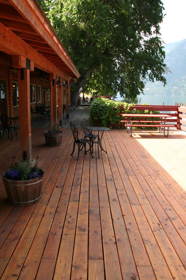 A wooden deck with tables and chairs outside a building.