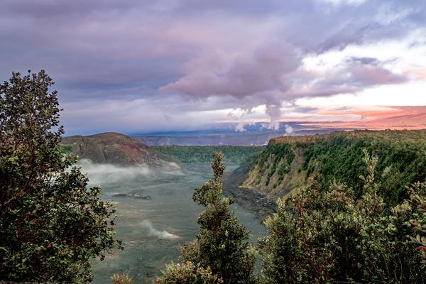 A volcanic crater at sunrise with trees in the foreground