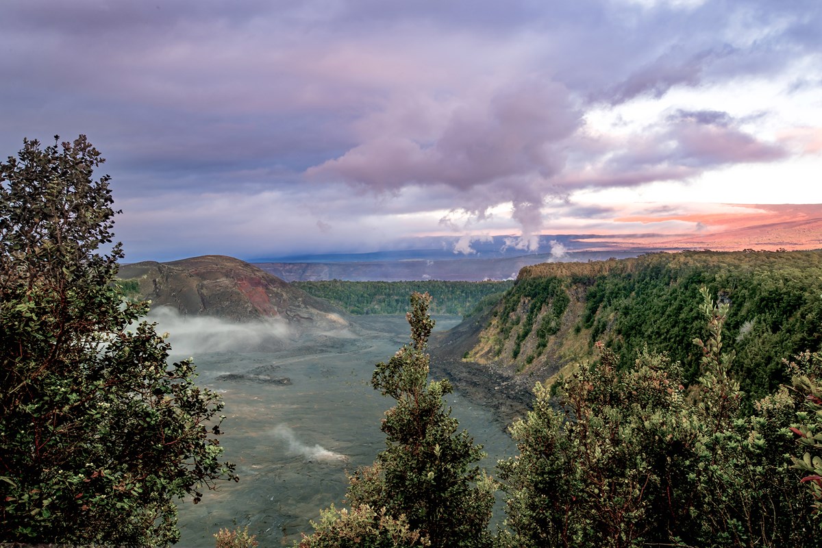 Volcanic crater at sunrise with trees in the foreground