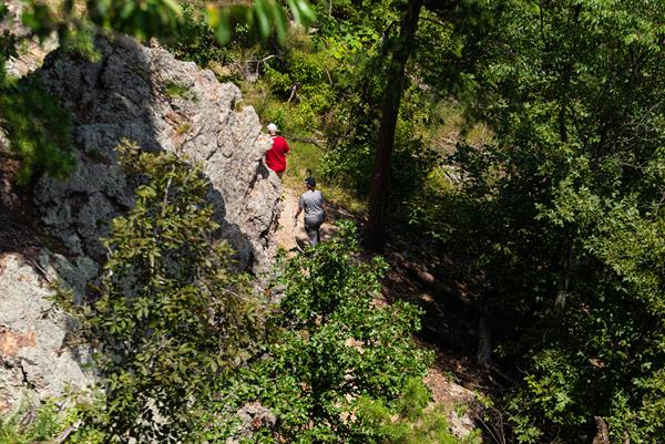 Two people hike along a rocky trail.