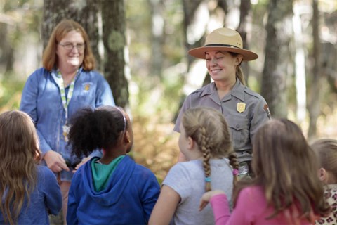 Two women in the woods with four children.