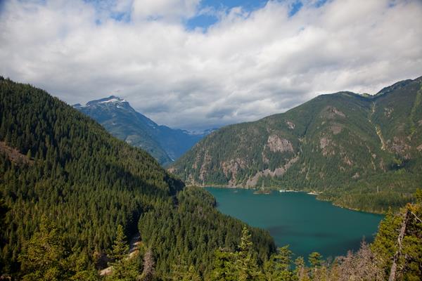 A blue lake surrounded by forested mountains.