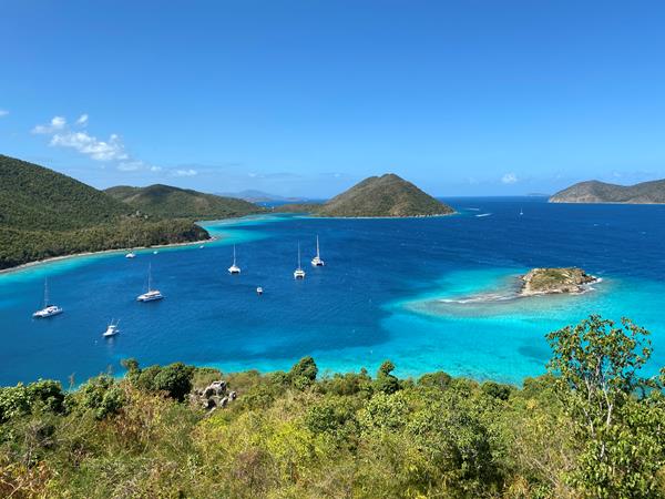 Distant boats dot turquoise water of varying shades on a brilliantly sunny day.