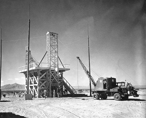 A black and white photo off a wooden tower and a crane.