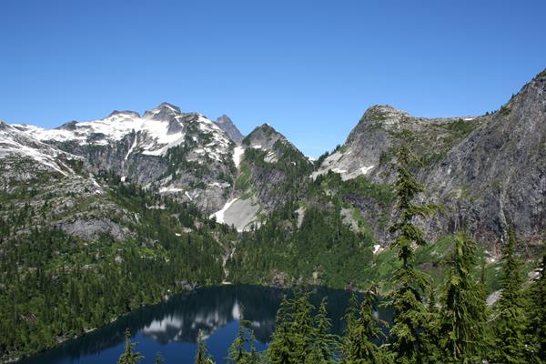 A blue lake surrounded by forested mountains.