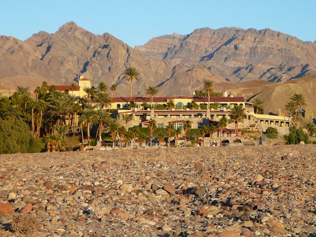 a large castle like structure with palm trees in a desert setting