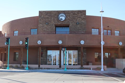 A rotund building made out of adobe and two stories tall sits under a blue sky.