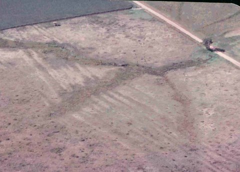 Aerial view of field with a row of deep furrows running through the middle.