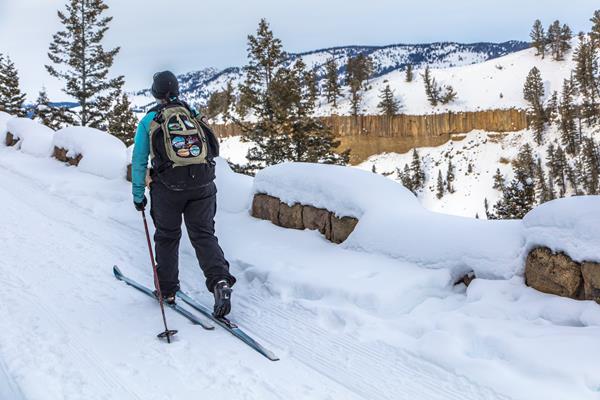 A skier travels along a trail on the edge of a canyon.