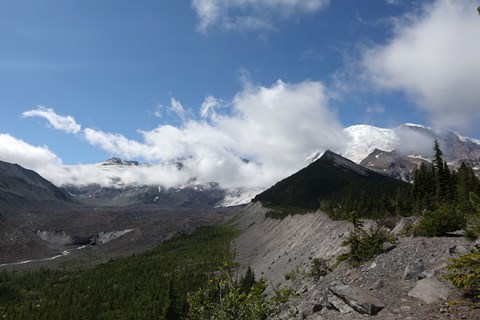 View of mountain with rocky glacier moraine with clouds partially covering glacier
